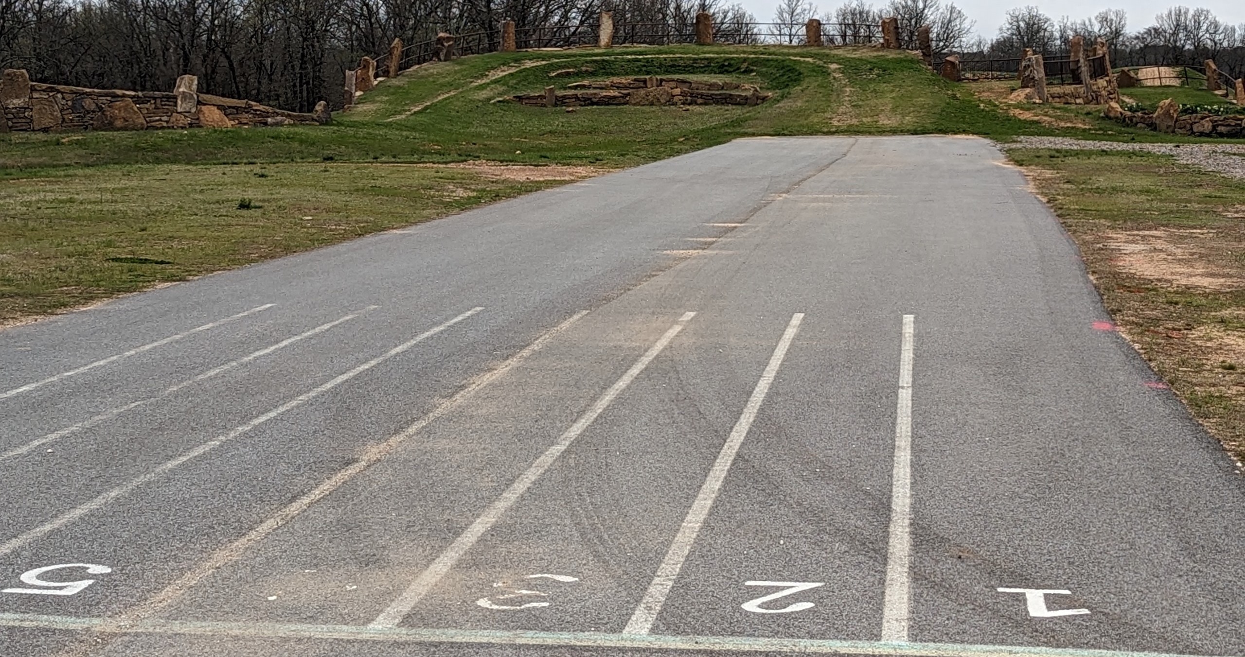 The start of a race track featuring line numbers painted onto the ground. The track starts as pavement and turns into an off-road course.