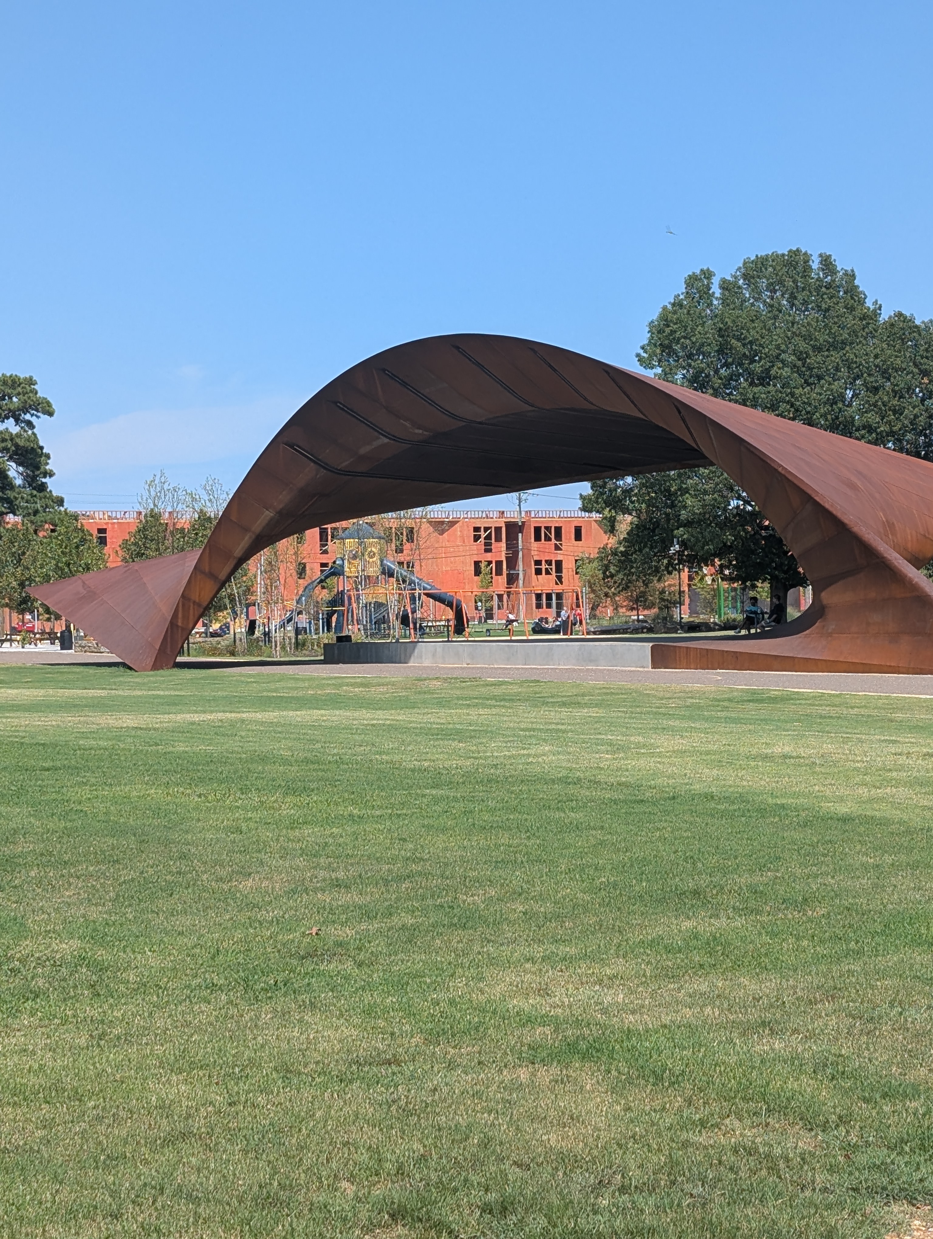 A scenic view of the paved walking trail at Luther George Park, surrounded by mature trees and well-maintained landscaping.